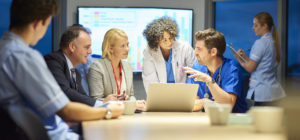 a mixed group of healthcare professional and business people meet around a conference table .