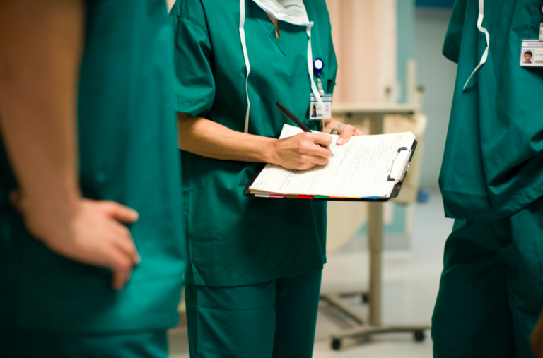 Three Doctors in Scrubs Writing on a Chart