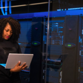 woman with computer standing near servers