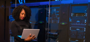 woman with computer standing near servers