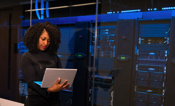 woman with computer standing near servers